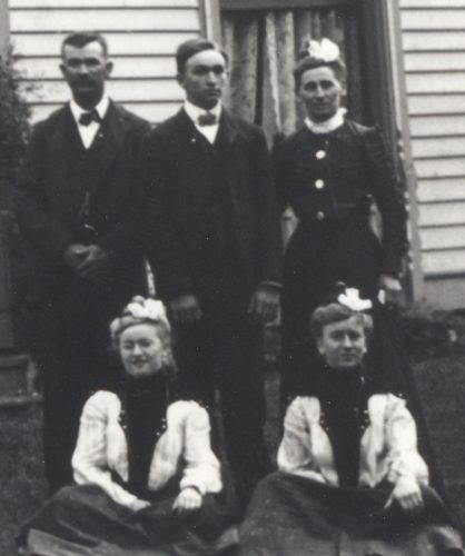 William Edward Roberts Family, 1900. Standing, from left: W. E. Roberts, son Orville Roberts, Orville’s mother, Mary M. (Main) Roberts. Seated on the ground in front of them are Maude Roberts & Clara Roberts, with Maude possibly having the lighter hair as seen in the 1892 photo. Cropped from a larger family photo.